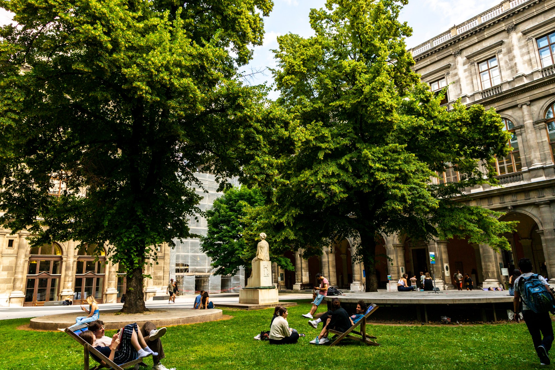 Estudantes a descontrair no pátio com arcadas da Universidade de Viena